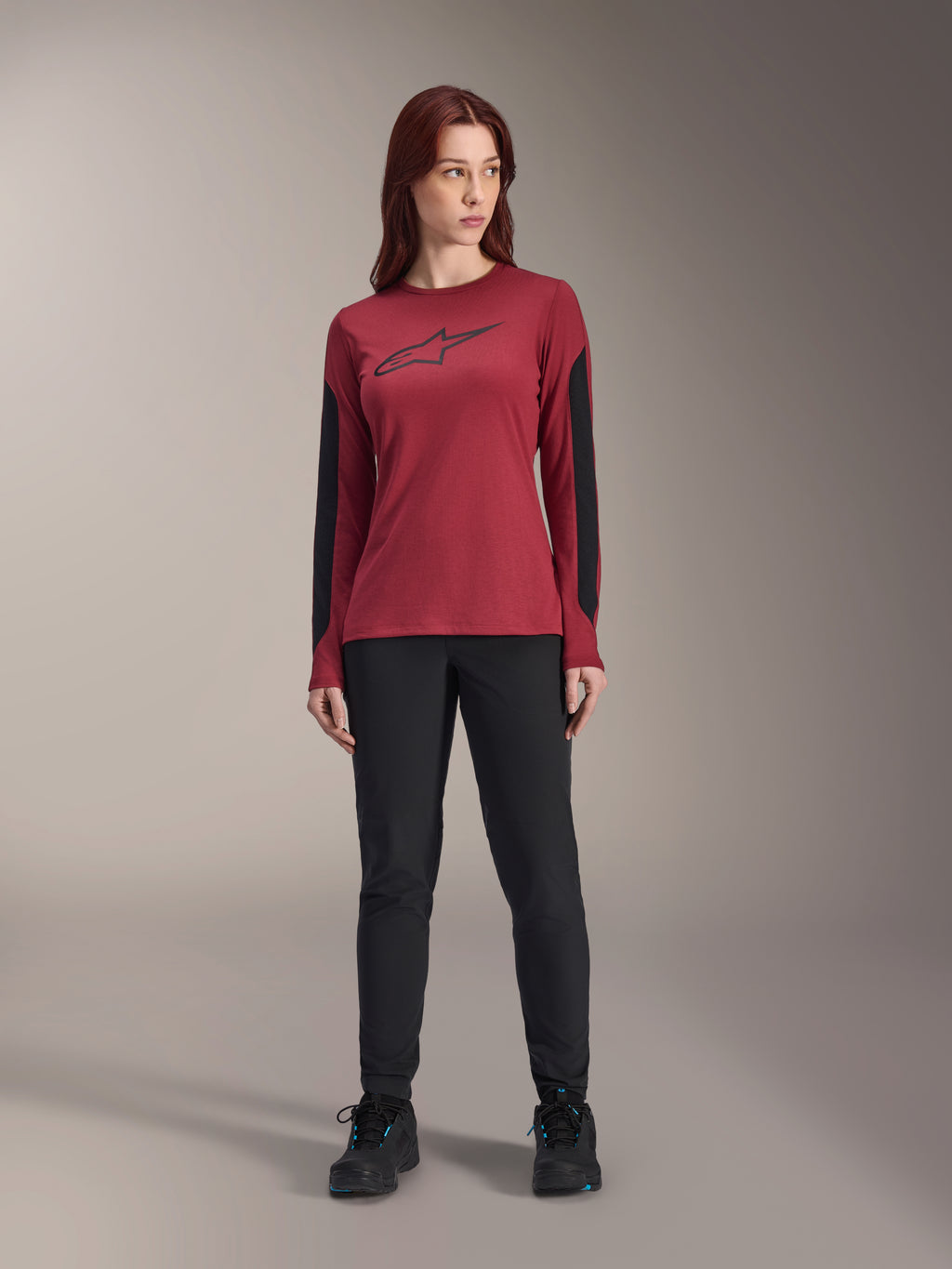 Camisola de manga comprida Alpinestars Stella A-Dura Dri Astar feminina em bordeaux, com o logótipo Astars preto no peito e painéis de malha pretos nas mangas, combinada com calças técnicas pretas e sapatilhas, vestuário de performance para BTT para mulher.
