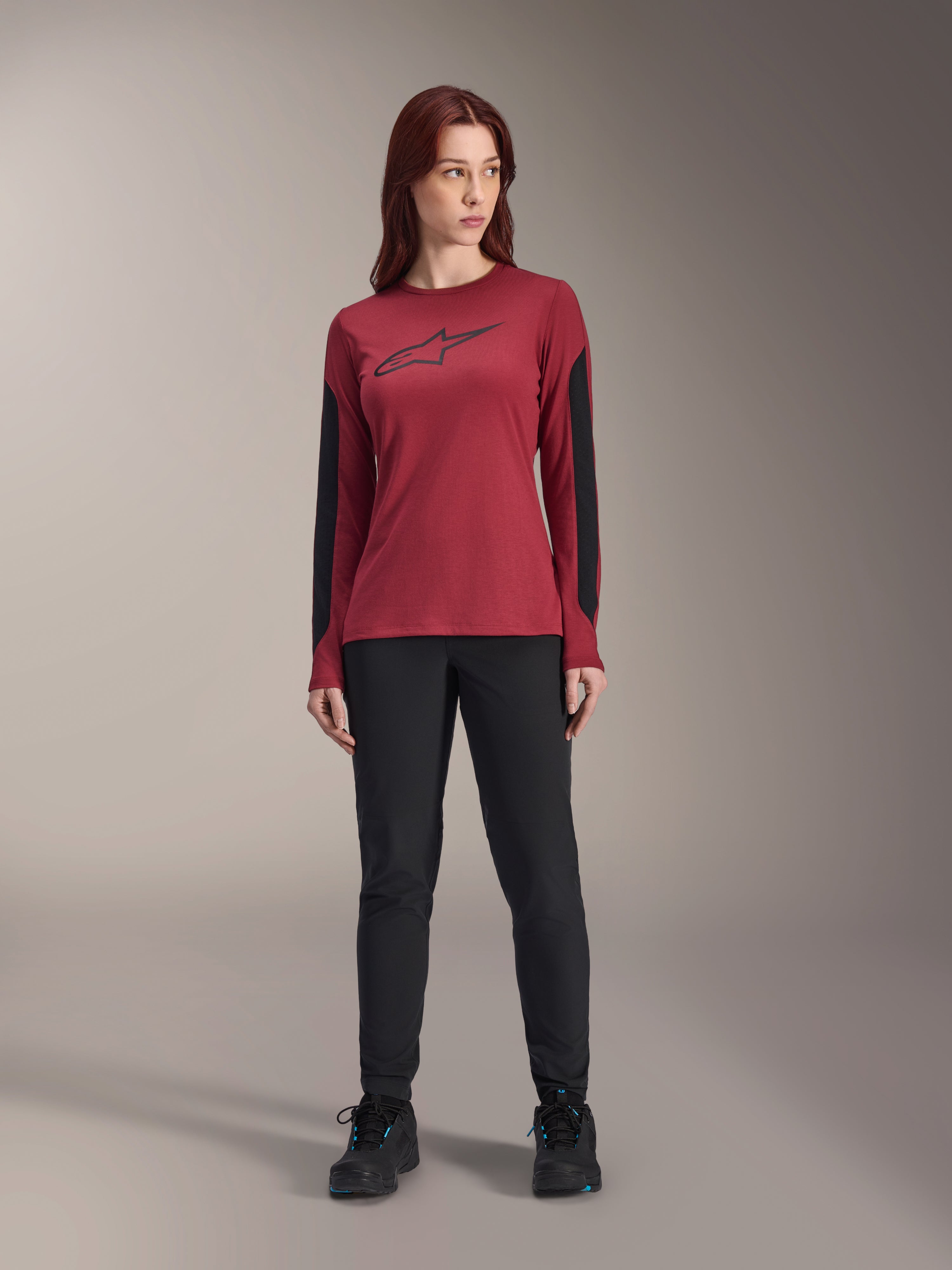 Camisola de manga comprida Alpinestars Stella A-Dura Dri Astar feminina em bordeaux, com o logótipo Astars preto no peito e painéis de malha pretos nas mangas, combinada com calças técnicas pretas e sapatilhas, vestuário de performance para BTT para mulher.