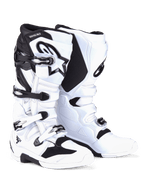 Botas Alpinestars Tech 7, botas de motocross, em branco e preto, com sistema de fecho de quatro fivelas com detalhes prateados e pretos, logótipo Alpinestars proeminente na canela e painéis de TPU reforçados para proteção em todo-o-terreno.