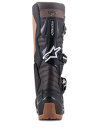 Botas Alpinestars Tech 7 Enduro, pretas e castanho escuro, vista traseira mostrando as zonas de flexão em acordeão no tendão de Aquiles e proteção em TPU, com logótipo da estrela Alpinestars em branco e detalhes no calcanhar em bege, design robusto para Enduro e todo-o-terreno