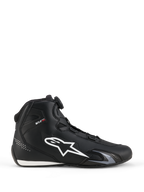 Alpinestars Celer Shoes, sapatos de motociclismo, pretos e brancos, perfil lateral com grande logótipo de estrela branco, mostrador do Sistema de Fecho Rotor para ajuste e silhueta elegante de performance desportiva