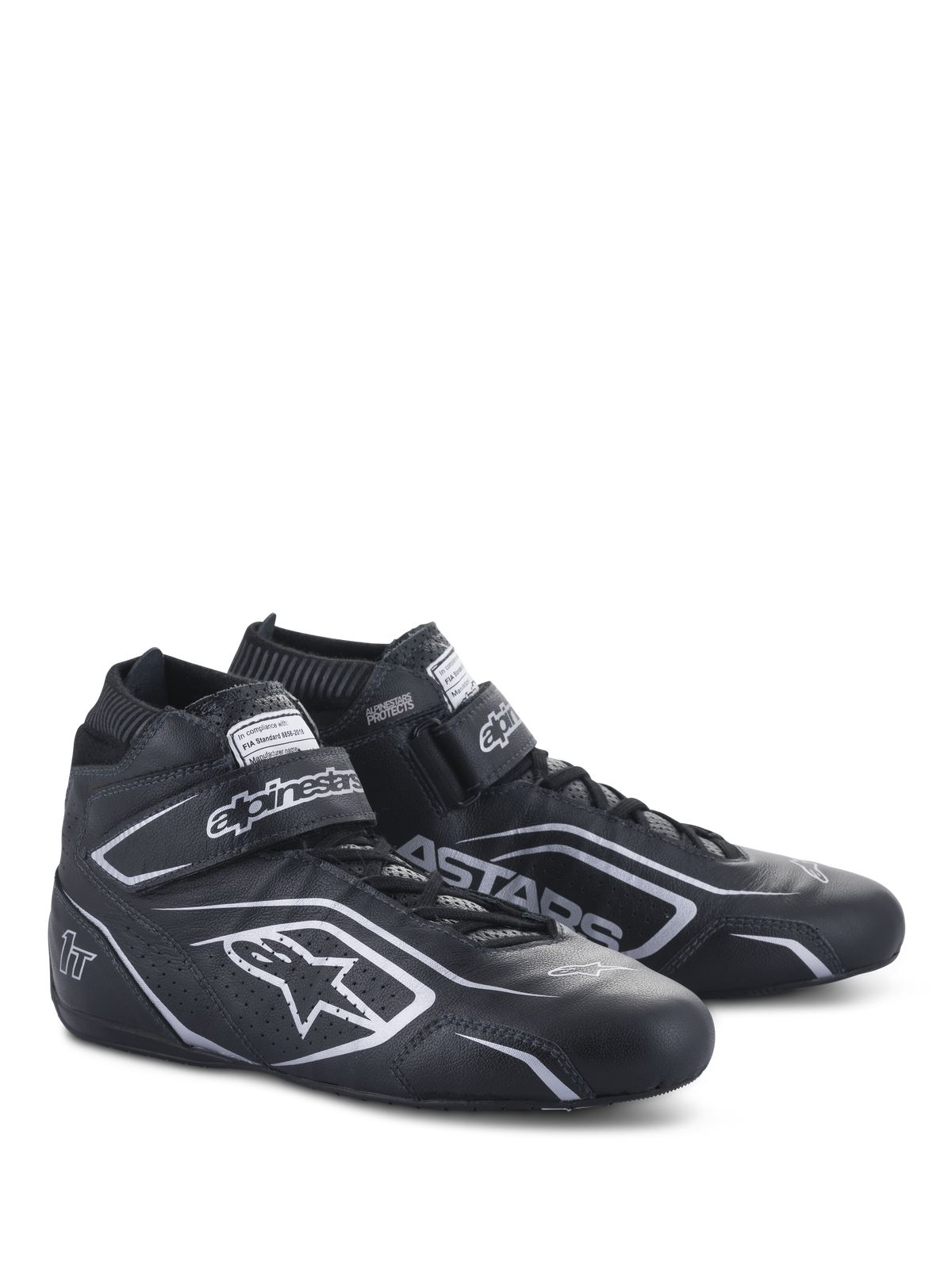 Sapatos Alpinestars Tech-1 T V3 FIA, sapatos de automobilismo, pretos e prateados, construção em couro bovino com logótipos e branding Alpinestars prateados, vista lateral angulada com tira de gancho e laço e fecho de cadarços