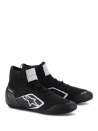 Alpinestars Supertech Shoes, Auto Racing Shoes, Black, featuring a fully knitted fire-retardant upper and carbon fiber heel cup, white Alpinestars logo on the side, FIA/SFI certification labels on the tongue, professional motorsport footwear with a sleek design