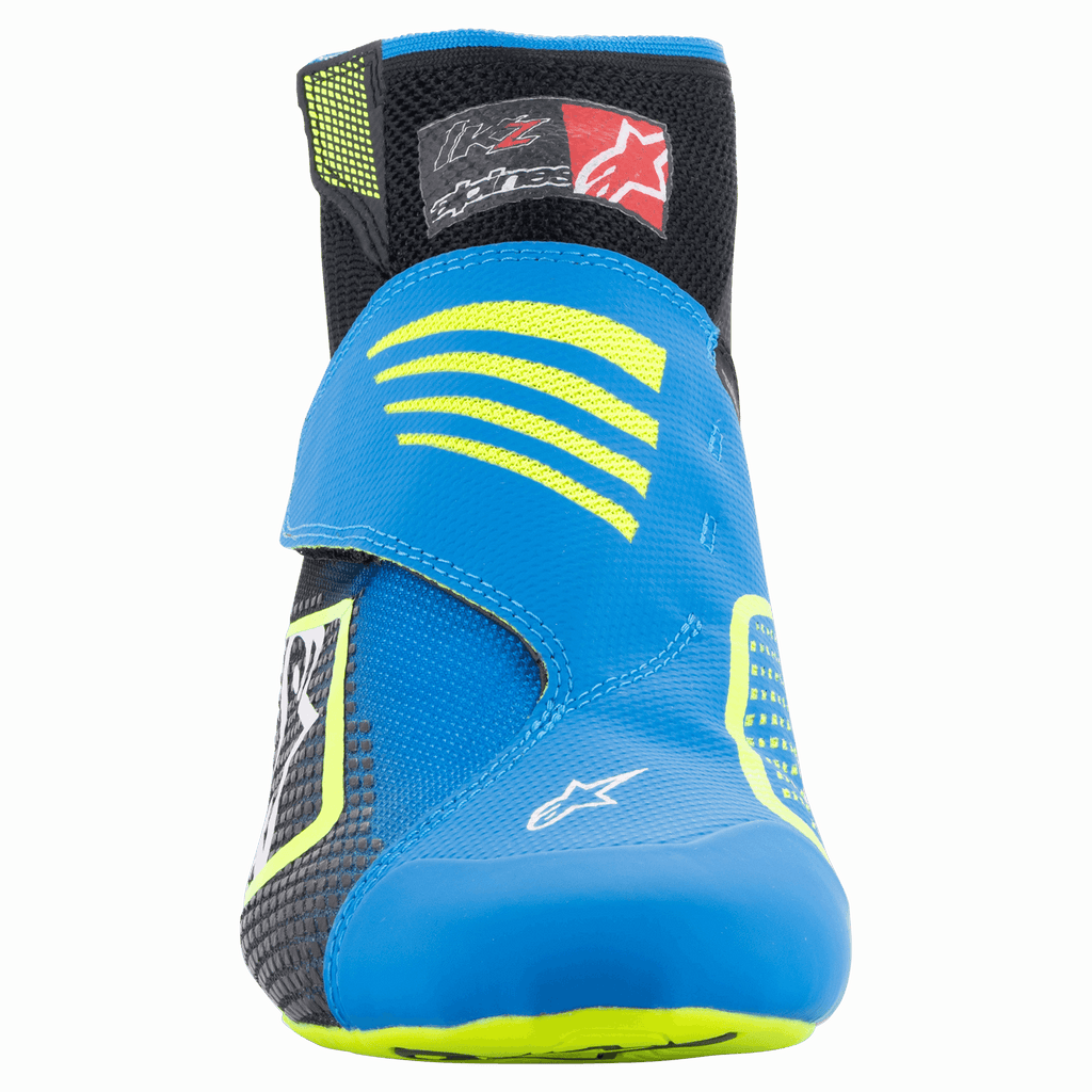 Sapatos Alpinestars Tech-1 KZ V2, Sapatos de Karting, Preto, Azul Enamel e Amarelo Fluo, vista frontal mostrando a parte superior tricotada sem costuras, tira azul vibrante com detalhes amarelos e colarinho de tornozelo preto.