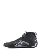 Alpinestars Tech-1 Z V3 Shoes FIA, sapatos de automobilismo, pretos e prateados, vista de perfil lateral, parte superior em couro bovino premium com um grande logótipo de estrela estilizada prateada, tira de velcro no tornozelo e design elegante de cano alto para desempenho profissional em automobilismo.