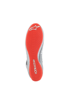 Sapatos Alpinestars Tech-1 Z V3 FIA, sapatos de automobilismo, cinzento escuro, preto e vermelho, vista inferior que mostra a sola de borracha vermelho brilhante com logótipos Alpinestars brancos, padrão de rasto assimétrico texturizado para aderência, detalhes em couro prateado na lateral