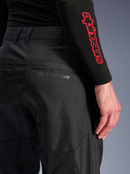 Alpinestars C-1 Air Pants, calças de motociclismo em tecido preto, vista aproximada do bolso traseiro com logótipo Alpinestars cinzento subtil, painéis de malha respirável e polifibra durável, concebidas para conforto na condução urbana