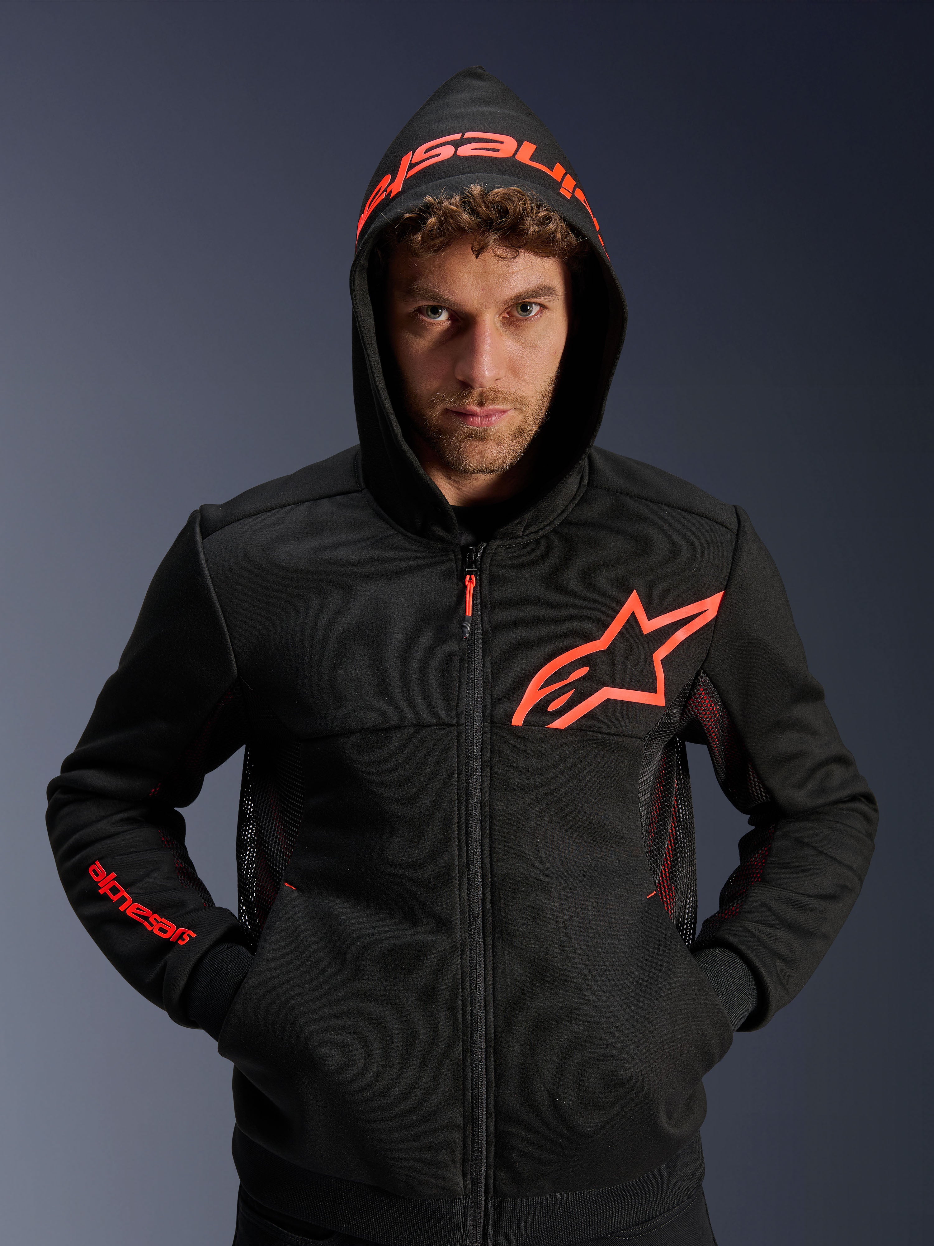 Alpinestars Chrome Air Sport Hoodie, preto e vermelho fluo, hoodie de motociclismo urbano com painéis de ventilação em malha, logótipo Astar vermelho no peito e capuz com marca, equipamento de condução casual para ambientes urbanos.