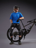 Camisola Alpinestars A-Dura Air SS azul e calções pretos camuflados com ciclista e bicicleta de BTT num estúdio.