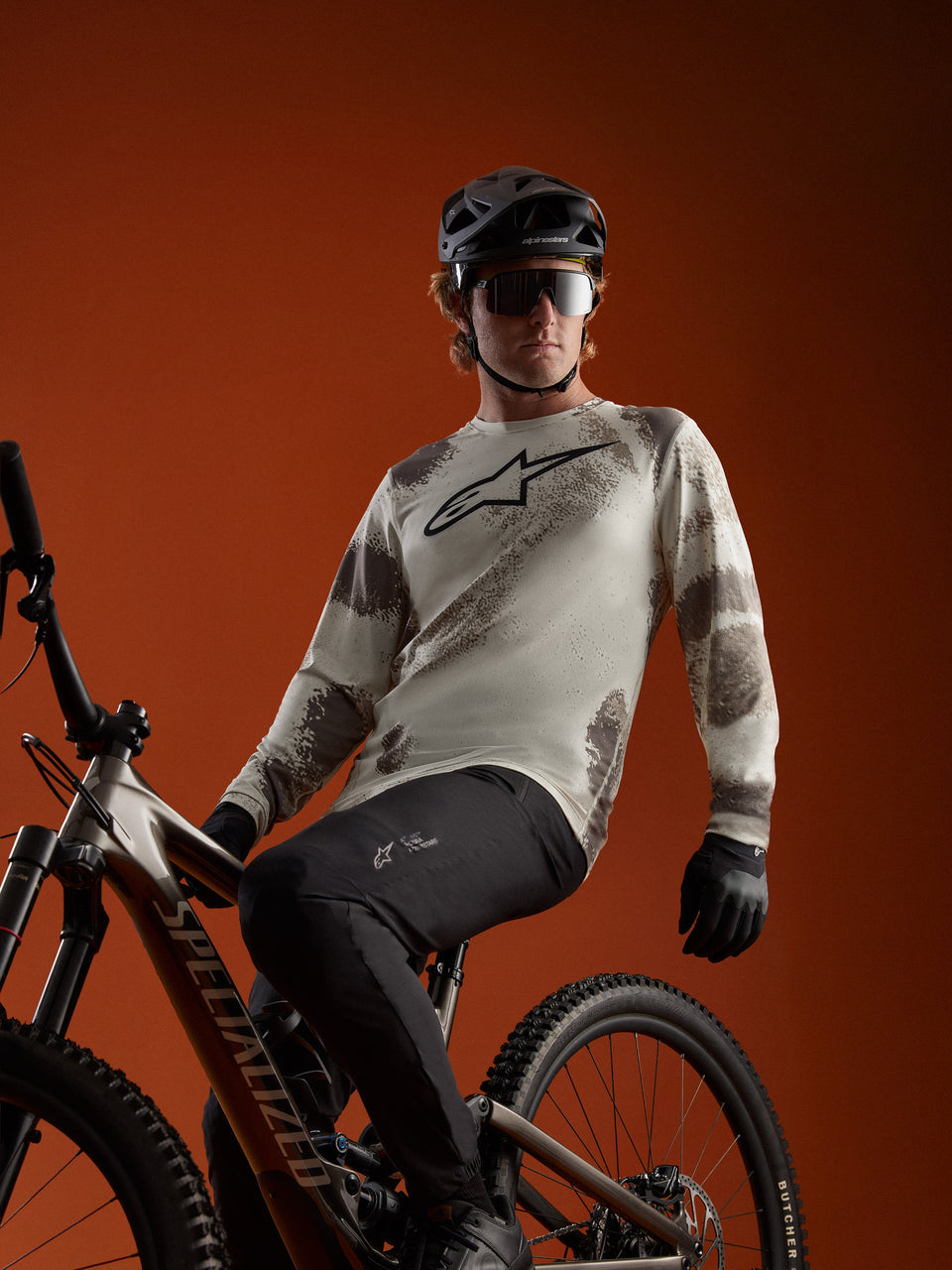 Alpinestars A-Dura Ride Jersey Sand Camo de manga comprida, com logótipo no peito, vestida por ciclista de BTT