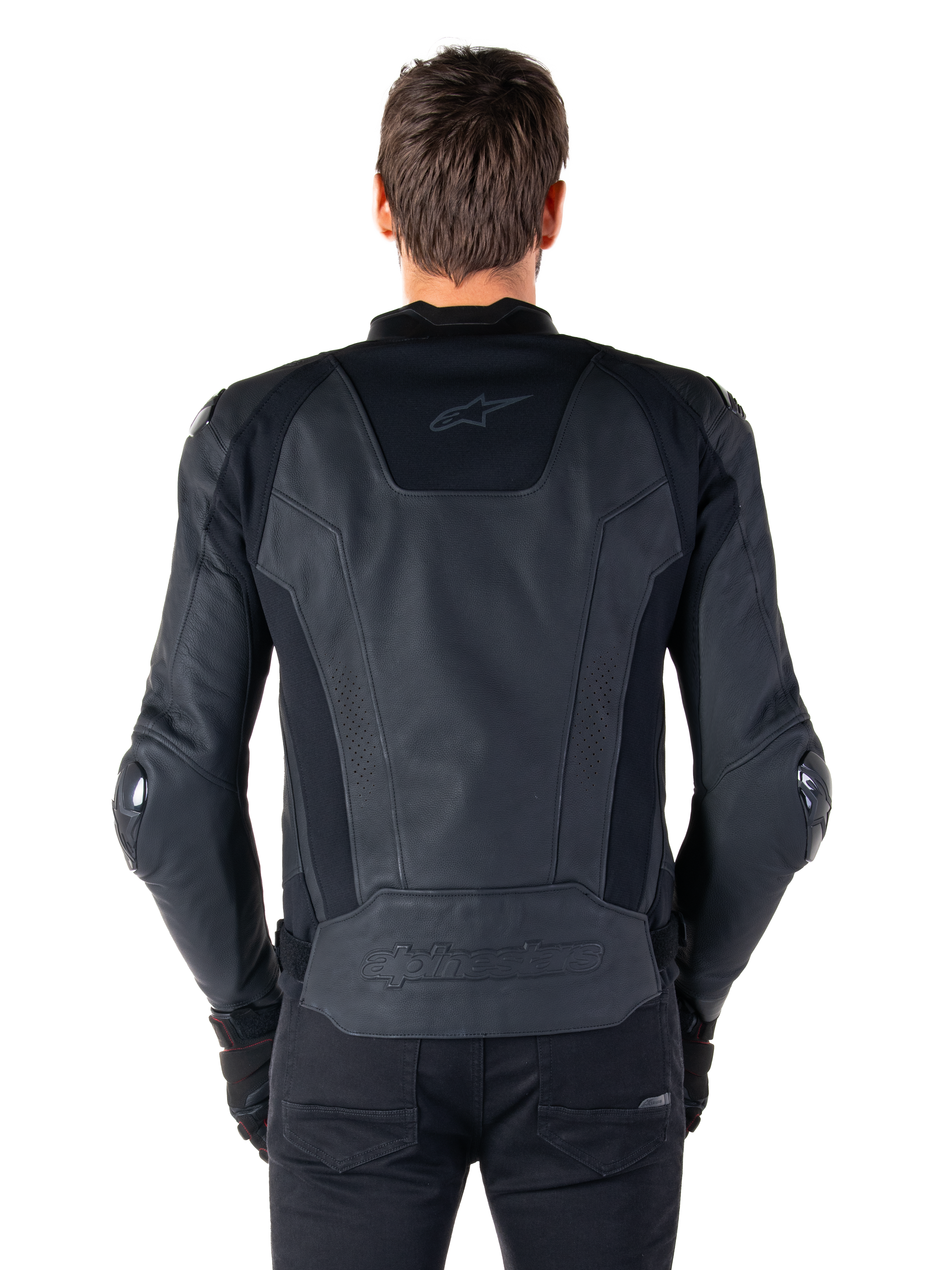 Rear view of a rider wearing the Alpinestars Missile V3 Leather Jacket in black, featuring premium leather construction with technical stretch panels, embossed Alpinestars logo on the lower back, and subtle branding on the upper back, paired with black pants for a coordinated racing sport look.