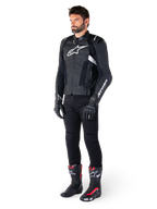 Male rider wearing the Alpinestars Missile V3 Leather Jacket in Black and White, featuring a white chest logo and perforated leather panels, paired with black riding pants, black gloves, and black and red racing boots for a complete sport riding look.