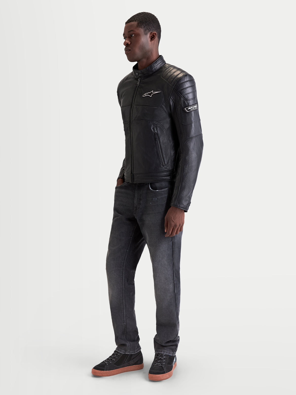 Alpinestars Revern casaco de moto para homem, casaco urbano em couro preto, vista de perfil lateral num modelo a mostrar o estilo heritage e a construção em couro bovino flor integral