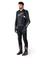Alpinestars Missile V3 Airflow Leather Jacket, Black and White, worn by a male model with black riding pants, black gloves, and racing boots with red and white accents, featuring perforated leather and white logo branding, performance motorcycle racing gear