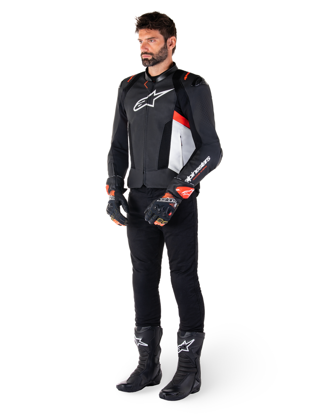 Alpinestars Missile V3 Airflow Leather Jacket, Black White Red Fluo, worn by a male model with black pants, black racing gloves, and black boots, featuring perforated leather for ventilation, a white chest logo, and red fluo accents, designed for premium racing and sport performance.