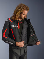 Casaco de Pele Alpinestars GP Force V2 em Preto e Vermelho Fluo, vista interior detalhada num modelo mostrando o colete térmico destacável e o bolso interno impermeável, construção em pele premium para proteção em condução desportiva.