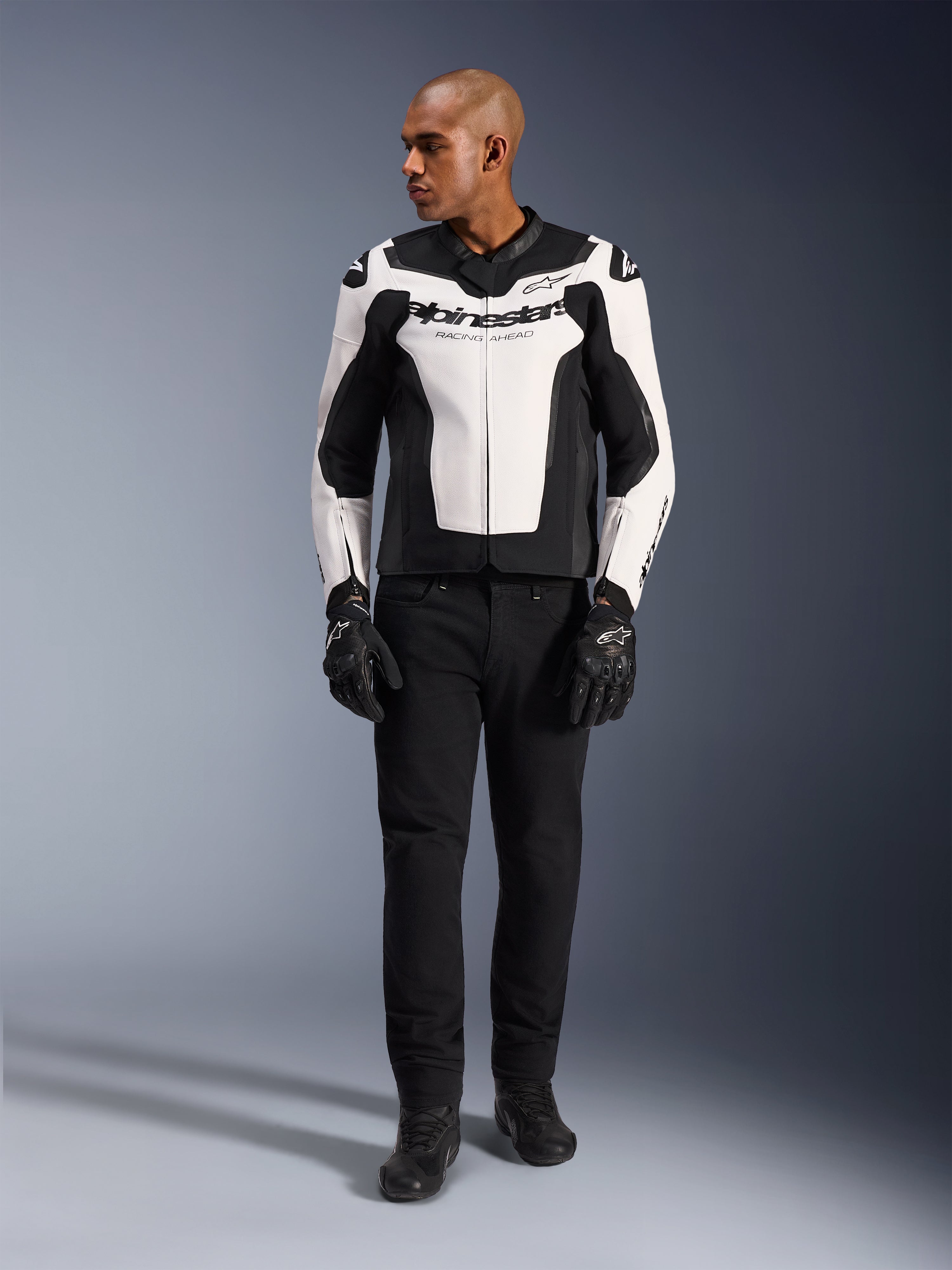 Alpinestars GP Force V2 Leather Jacket, White and Black, full-body view on a model wearing black pants and gloves, featuring multi-panel leather construction with Alpinestars branding on the chest and sleeves, sporty design for motorcycle riding