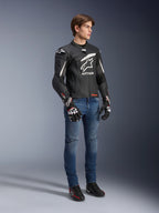 Alpinestars GP Plus R V4 Rideknit Leather Jacket, preto e branco, casaco de motociclismo em couro usado por um modelo com calças de ganga azuis e luvas pretas, com um logótipo Astars branco proeminente no peito, painéis perfurados e detalhes brancos nos ombros.