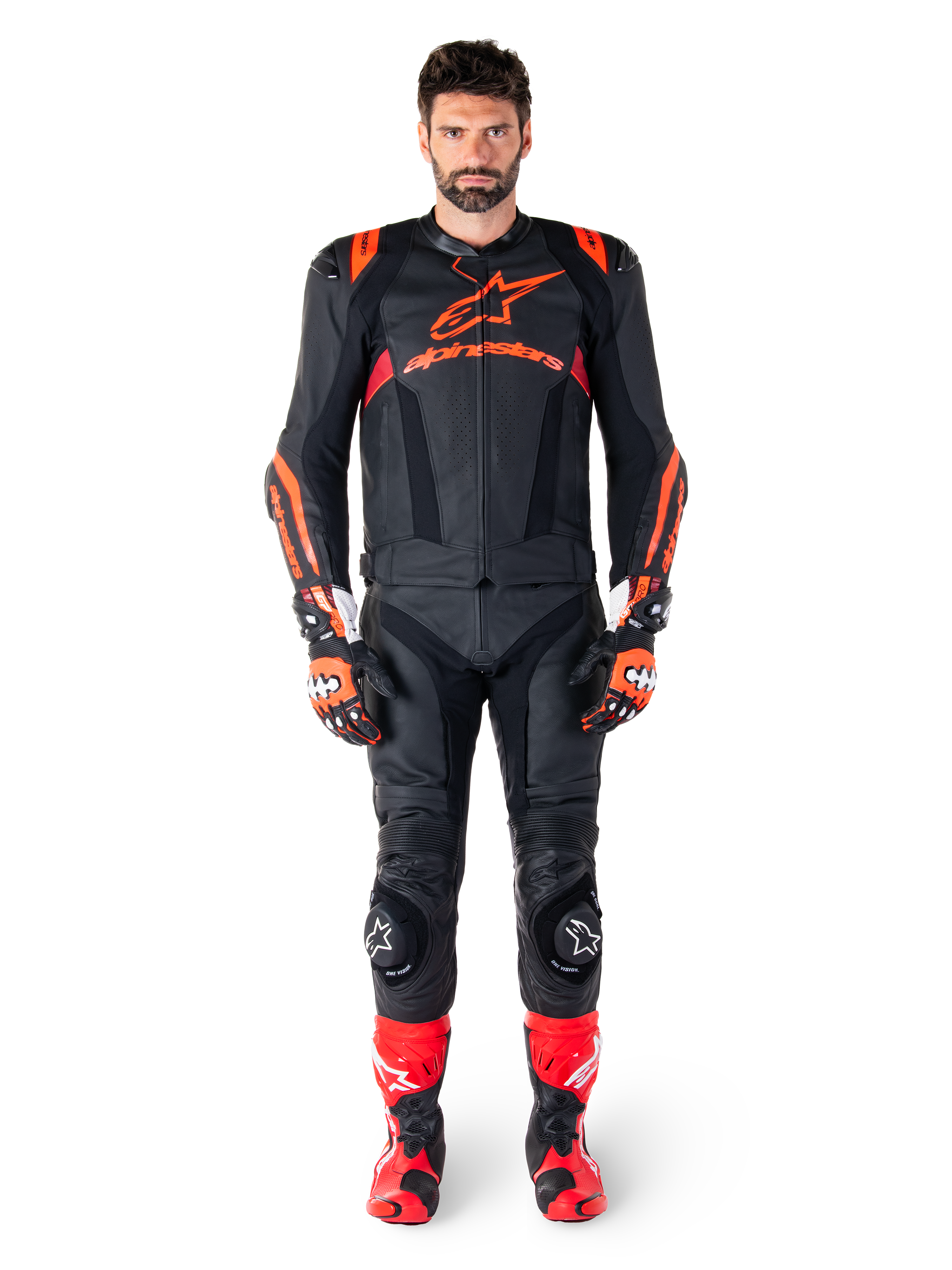 Male model wearing Alpinestars Missile V3 Ignition Leather Jacket in Black Red Fluo Dark Red, complete motorcycle racing gear including matching leather pants, racing gloves, and boots, featuring bold Alpinestars branding on the chest, forward-facing pose, professional sport riding outfit