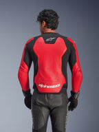 Alpinestars GP Force V2 Air Leather Jacket in Red and Black, rear view showing the perforated leather chassis for airflow, white Alpinestars branding on the lower back, and integrated stretch panels, worn with black leather motorcycle pants and gloves.