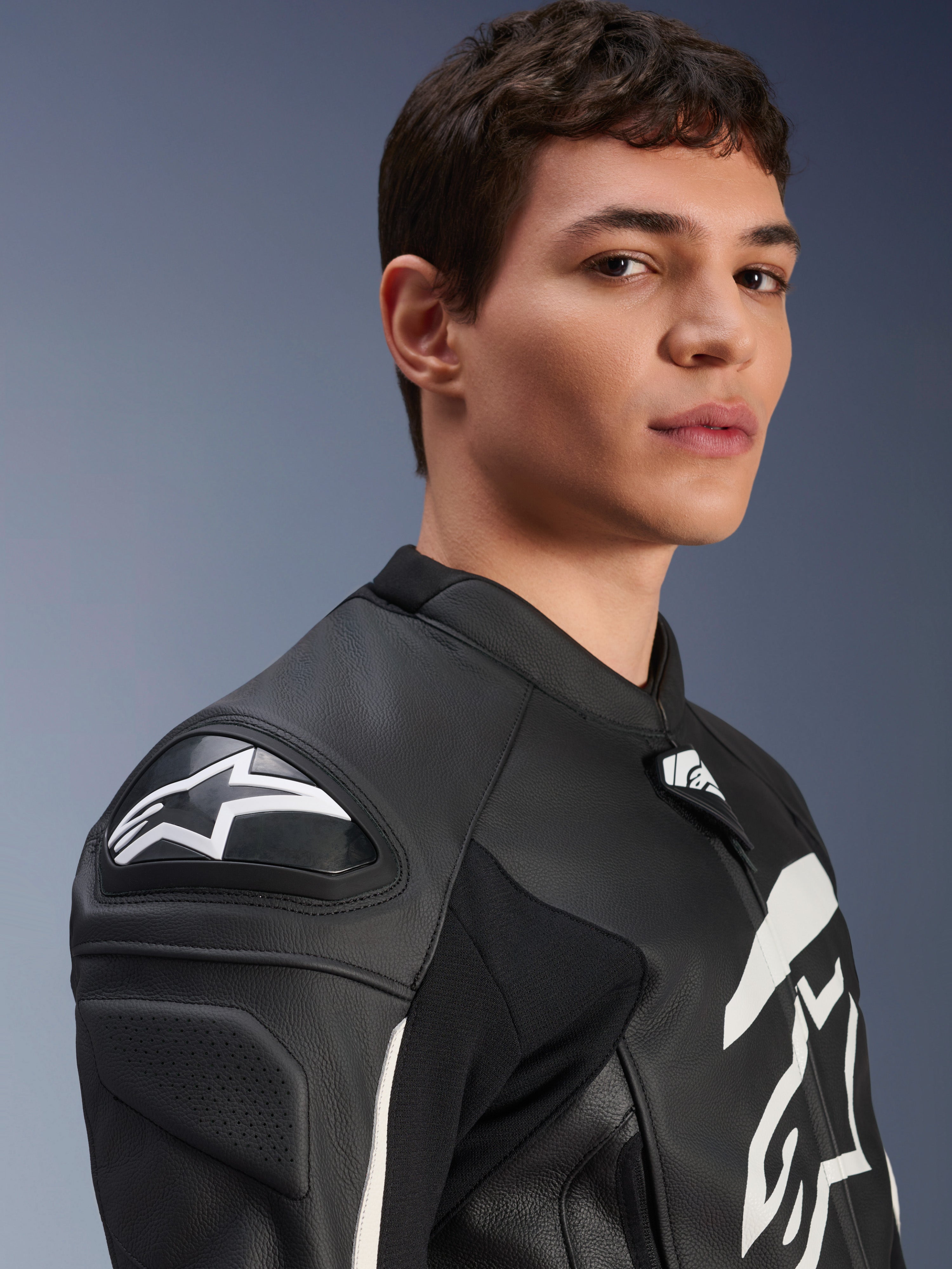 Casaco de Couro Alpinestars GP Plus V4, preto e branco, vestido por um modelo masculino, apresentando o logótipo Alpinestars em branco e deslizadores de ombro DFS, construção em couro derivada da competição para condução desportiva