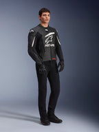 Alpinestars GP Plus V4 Leather Jacket, casaco de motociclismo desportivo, preto e branco, vestido por um modelo masculino com calças e luvas pretas, com um grande logótipo ASTARS branco no peito e sliders de ombro externos DFS, design profissional derivado das corridas