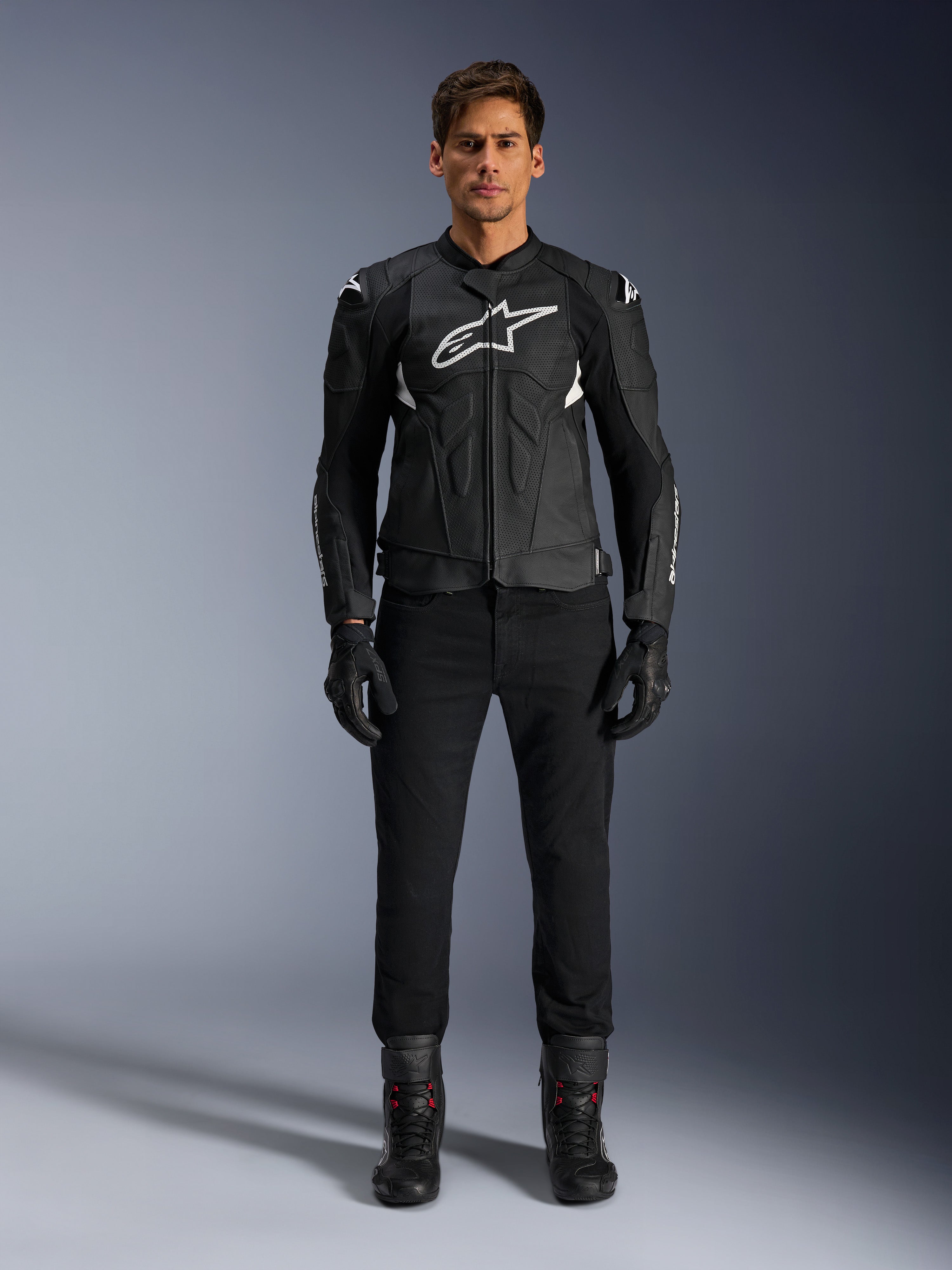 Alpinestars Dusk Airflow Leather Jacket, casaco de motociclismo em couro, preto e branco, com painéis perfurados para fluxo de ar, logótipo Astars branco no peito, usado por um piloto masculino com calças pretas, luvas e botas de condução, fotografia de estúdio profissional para equipamento de motociclismo desportivo.