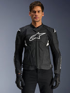 Alpinestars Dusk Airflow Leather Jacket, casaco de motociclismo em pele, preto e branco, vestido por um modelo, com painéis de pele perfurada para ventilação, logótipo branco grande no peito e sliders externos nos ombros