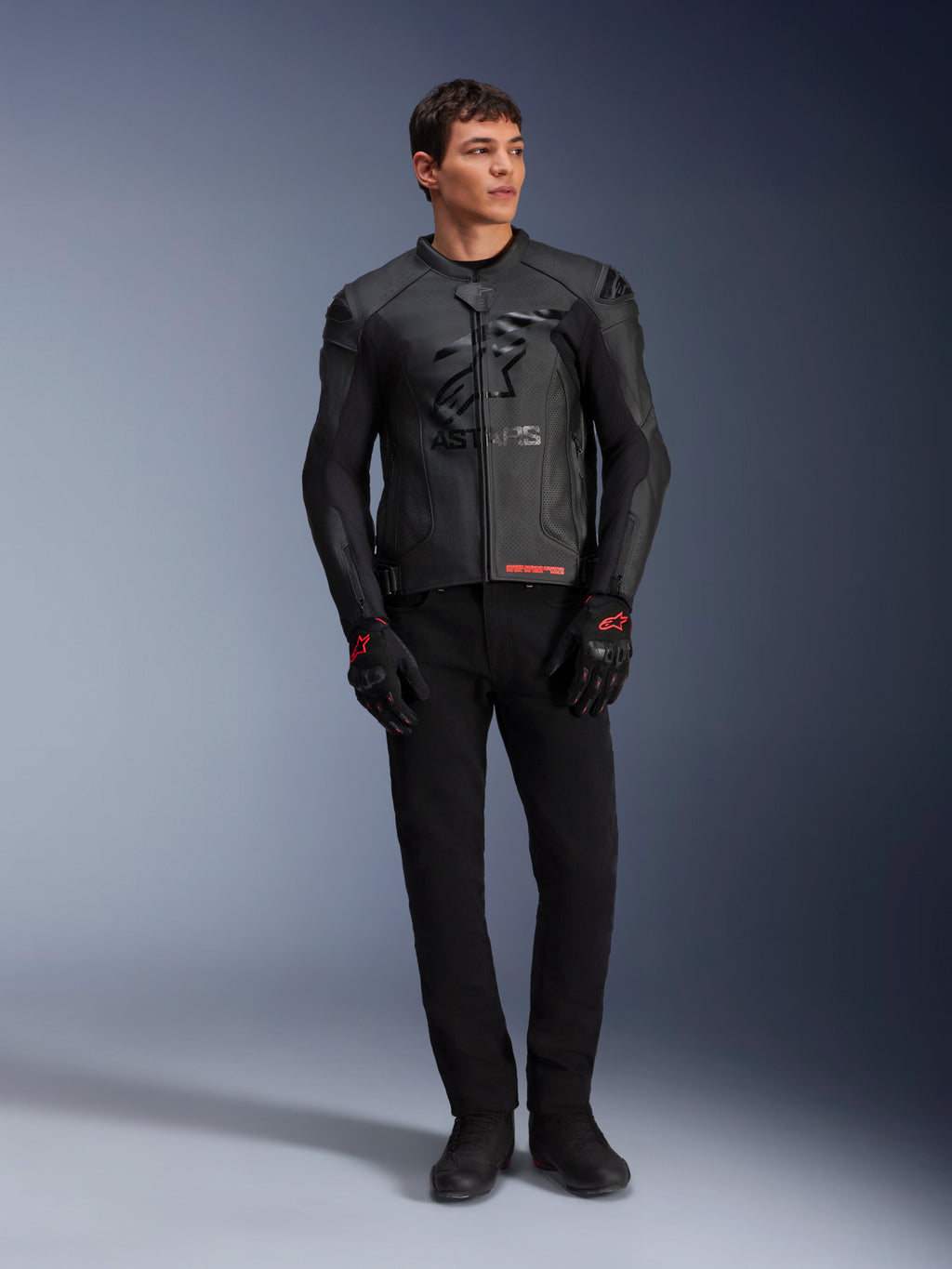 Jaqueta de Couro Alpinestars GP Plus R V4 Airflow, preta, vestida por um modelo masculino com luvas e calças pretas a condizer, com painéis de couro perfurado, um grande logótipo de estrela tonal no peito e um ajuste desportivo elegante