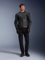 Jaqueta de Couro Alpinestars GP Plus R V4 Airflow, preta, vestida por um modelo masculino com luvas e calças pretas a condizer, com painéis de couro perfurado, um grande logótipo de estrela tonal no peito e um ajuste desportivo elegante