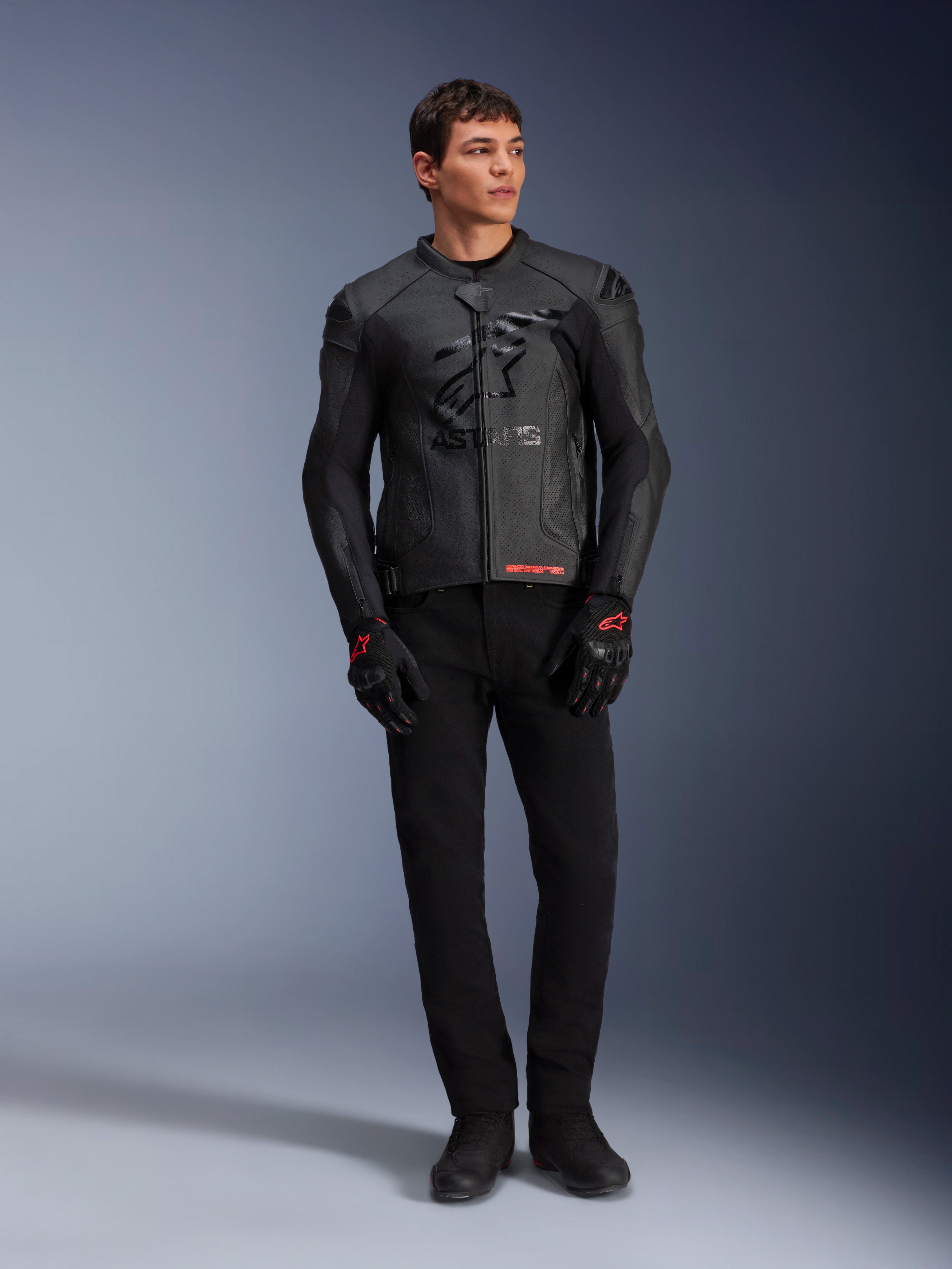 Jaqueta de Couro Alpinestars GP Plus R V4 Airflow, preta, vestida por um modelo masculino com luvas e calças pretas a condizer, com painéis de couro perfurado, um grande logótipo de estrela tonal no peito e um ajuste desportivo elegante