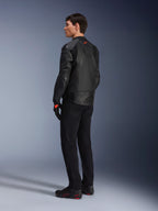 Jaqueta de Couro Alpinestars GP Plus R V4 Airflow, jaqueta de motociclismo desportiva para homem, totalmente preta, vista traseira de três quartos num modelo, com painéis de couro perfurado, logótipo vermelho nas costas e proteção de ombros integrada, usada com calças pretas e sapatos de condução
