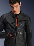 Jaqueta de couro Alpinestars GP Plus R V4 Airflow em preto, modelo masculino a abrir parcialmente o fecho frontal para mostrar a marca interna cor de laranja, com painéis de couro perfurado e logótipo brilhante no peito, combinada com uma luva de motociclismo preta e vermelha