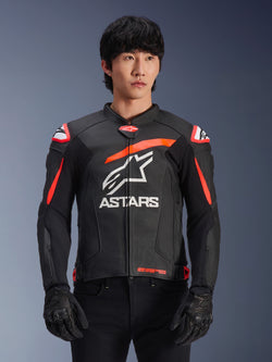 Casaco de pele Alpinestars GP Plus R V4 Airflow em preto com detalhes vermelho fluo e branco, vestido por um modelo, com construção em pele perfurada, um logótipo ASTARS branco de grandes dimensões no peito e proteção de ombro integrada para motociclismo de competição.