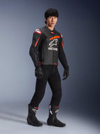 Male rider wearing Alpinestars GP Plus R V4 Airflow Leather Jacket, Black with Red Fluo and White accents, featuring perforated leather and ASTARS chest logo, worn with black riding pants and black motorcycle boots, sport performance gear