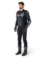 Modelo a usar o casaco de couro Alpinestars Faster V3 Airflow, preto e branco, com couro perfurado e logótipos Alpinestars brancos, combinado com calças, luvas e botas de condução pretas, equipamento de motociclismo desportivo