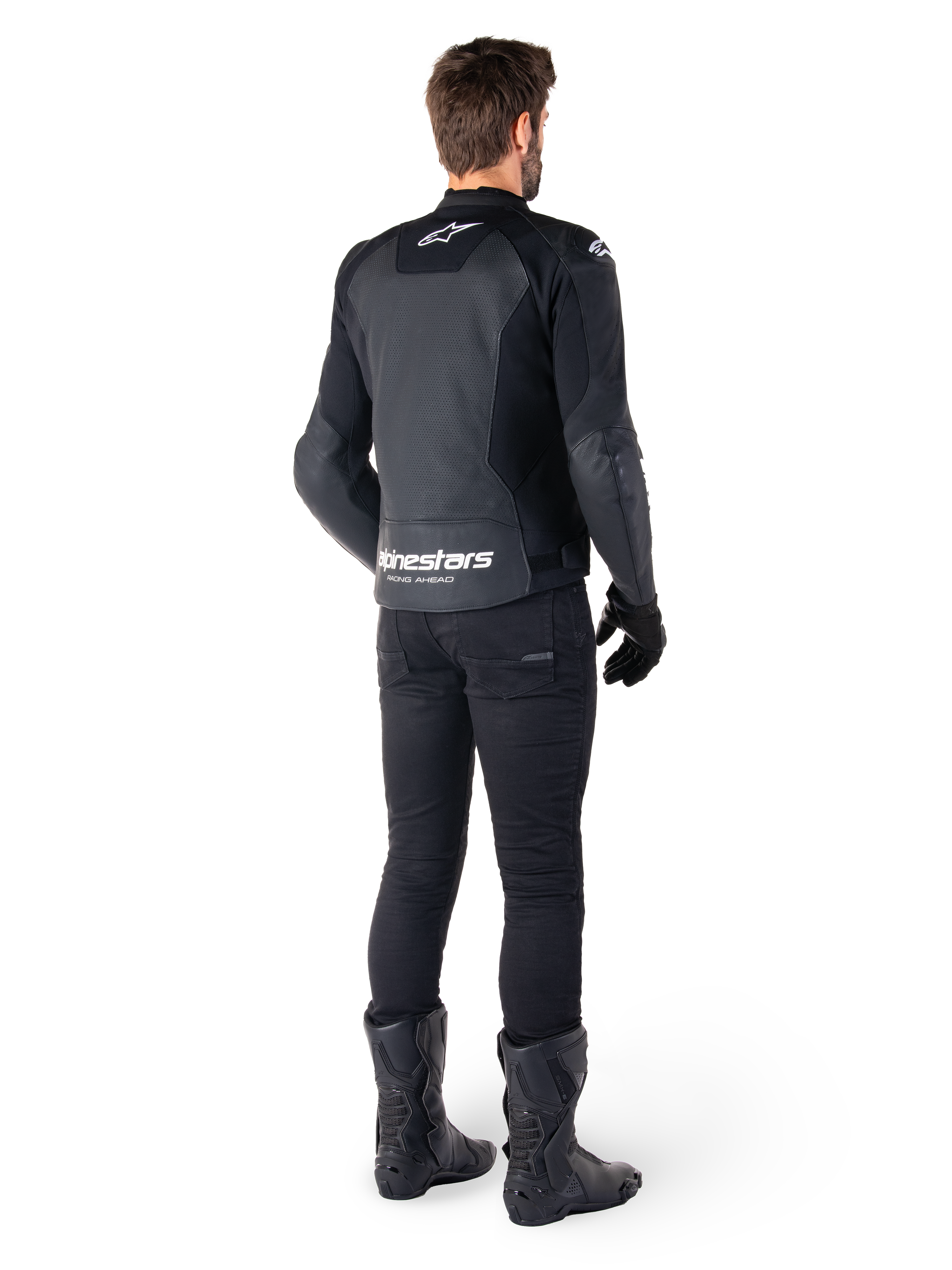 Casaco de couro Alpinestars Faster V3 Airflow, preto e branco, vista traseira com painéis de couro perfurado e marca Alpinestars proeminente na zona lombar, usado por um motociclista com calças, luvas e botas de condução pretas