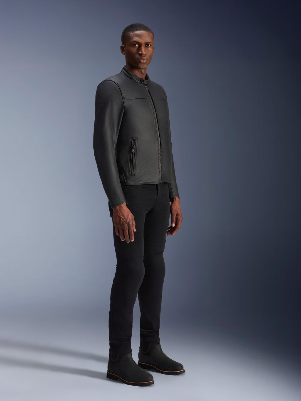 Male model wearing Alpinestars Blacktrack Leather Jacket, Black on Black, modern biker style with premium leather and metallic zip details, paired with black pants and boots for a contemporary urban look