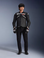 Model wearing the Alpinestars Atem V5 Leather Jacket in Black and White, featuring white Alpinestars branding and a red star logo on the chest, paired with black pants and black and white racing gloves, sleek performance motorcycle gear