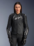 Woman model wearing the Alpinestars Stella Dusk Leather Jacket, Women's Motorcycle Jacket in Black and White, featuring premium leather construction, padded chest and shoulder protection, and front zipper closure, styled with black riding gloves.