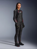 Casaco de Couro Stella Dusk Feminino da Alpinestars, Preto, Rosa Diva e Branco, usado por uma modelo com calças e botas de motociclismo pretas, apresentando uma construção em couro elegante com detalhes em rosa e logótipo branco.