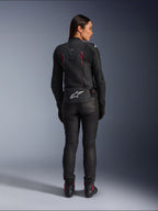 Casaco de Couro Alpinestars Stella Dusk, vista traseira, couro preto com detalhes em Diva Pink e branco, apresenta logótipo Alpinestars branco na parte inferior das costas e pormenores de ventilação cor-de-rosa, usado com calças e botas de condução pretas, equipamento de motociclismo desportivo premium para mulher
