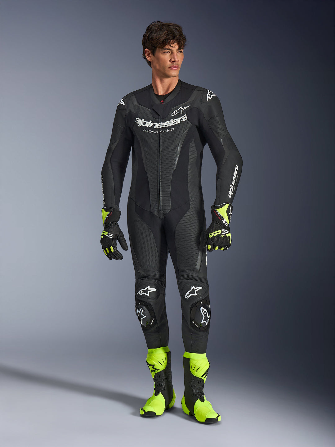 Alpinestars GP Force V2, fato de corrida de motociclismo de uma peça, preto com logótipos brancos, luvas e botas amarelo néon, proteção nos joelhos e cotovelos, construção em pele premium com zonas reforçadas