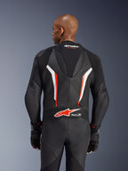 Alpinestars GP Force V2 Leather Suit, fato de motociclismo de 1 peça, preto, branco e vermelho fluo, vista traseira da parte superior do corpo mostrando a pele perfurada e o logótipo Tech-Air Ready, usado com luvas pretas e vermelhas a condizer