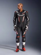 Alpinestars GP Force V2 Leather Suit - 1 Peça, preto, branco e vermelho fluo, vista de corpo inteiro de modelo masculino a usar equipamento profissional de motociclismo com luvas e botas a condizer, com painéis de pele perfurada e sliders de proteção nos joelhos.