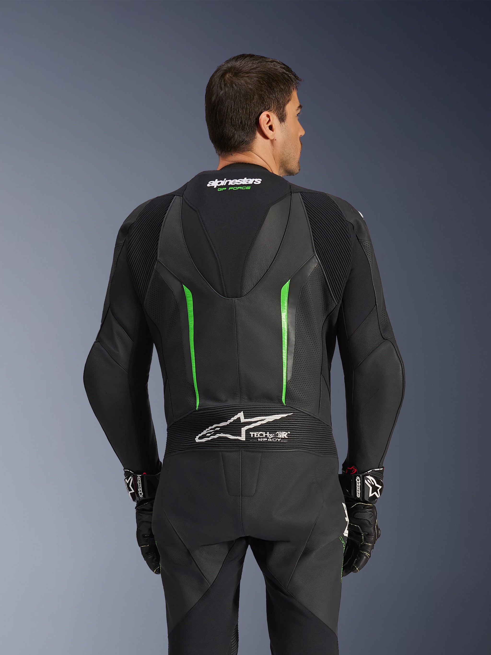 Alpinestars GP Force V2 Leather Suit - 1 Peça, preto e verde, vista traseira com corcova aerodinâmica, logótipo Tech-Air Ready, zonas de pele perfurada e painéis elásticos sanfonados para motociclismo de competição