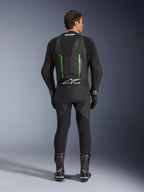 Vista traseira do Fato de Pele Alpinestars GP Force V2 de 1 Peça em preto e verde, com corcova aerodinâmica, painéis perfurados e logótipo Tech-Air Ready na zona lombar, usado com luvas e botas de corrida pretas.