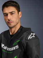 Fato de Pele Alpinestars GP Force V2 - 1 Peça, preto e verde, grande plano de um modelo masculino a usar o fato de corrida para motociclista, com logótipos em branco e verde, painéis de pele perfurada e proteção de ombro DFS Lite com logótipo de estrela branco.