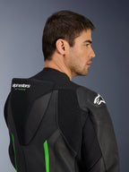 Grande plano da parte superior das costas e ombro de um modelo masculino a usar o Fato de Pele Alpinestars GP Force V2 em preto e verde, destacando a corcova aerodinâmica com a marca 'GP FORCE' em verde, um logótipo Astars branco no ombro e painéis sanfonados.
