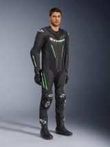 Alpinestars GP Force V2 Leather Suit 1-Piece, preto e verde, equipamento de corrida completo usado com luvas e botas pretas, com painéis de pele perfurada, logótipos Alpinestars brancos e deslizadores de joelho integrados, fato de performance profissional para pista